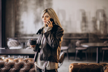 Young woman drinking coffee and talking on the phone in a cafe