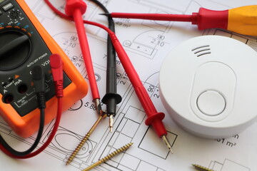 smoke detector with a screwdriver and a measuring device on a circuit diagram