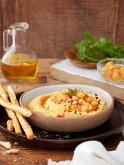 Homemade hummus with bread sticks and parsley on wooden background copy space. Selective focus.