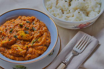 Chicken korma with a bowl of white rice.
