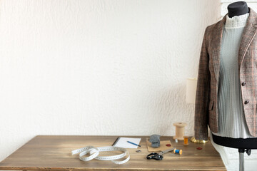 Suit jacket on tailor mannequin and sewing tools. Concept of clothes atelier