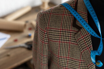 Suit jacket on tailor mannequin and sewing tools. Concept of clothes atelier