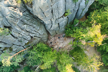 Aerial view of bright landscape with green forest trees and big rocky boulders between dense woods in summer. Beautiful scenery of wild woodland.