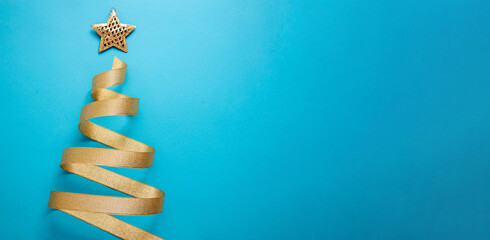 Christmas tree shape golden ribbon on blue background. Shiny star on top. Merry Xmas card