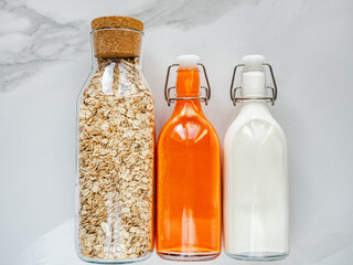 Three bottles with juice, milk, oatmeal and slices of vegetables lying on the table