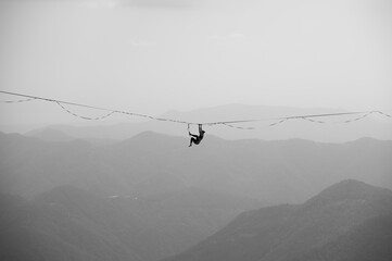 Persona appesa in equilibrio sulla corda slackline a grandi altezze tra le montagne sport estremo...