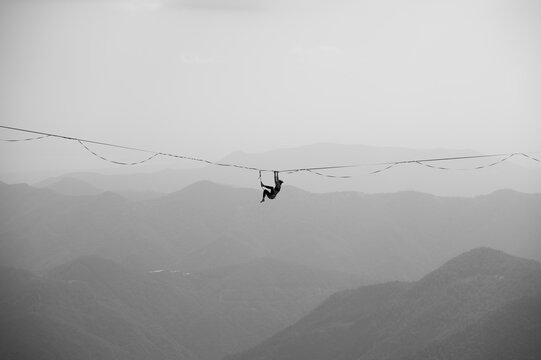 Persona appesa in equilibrio sulla corda slackline a grandi altezze tra le montagne sport estremo highline