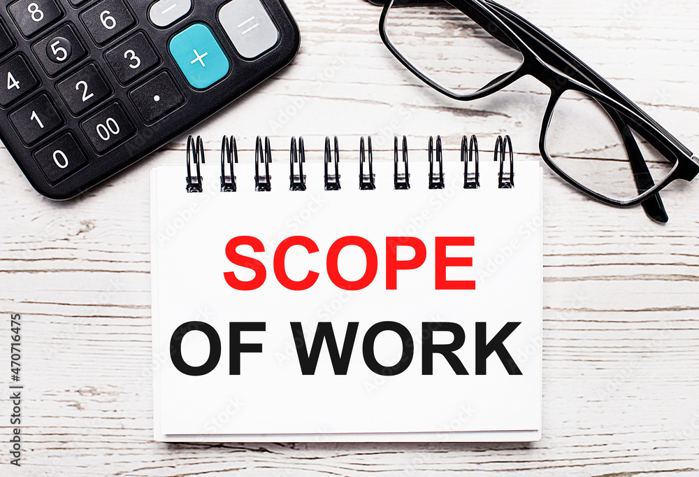 Poster on a light wooden table calculator, glasses and a blank notepad with the text scope of work. busines