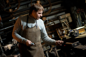 The portrait of blacksmith preparing to work metal on the anvil