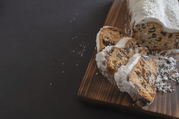 Traditional Christmas stollen made of dried fruits and nuts sprinkled with powdered sugar on the...