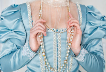 Hands of woman in beautiful medieval dress holding beads