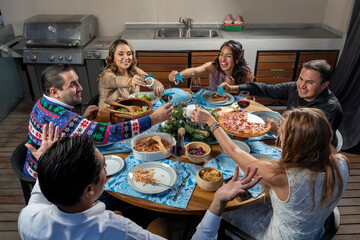 friends smiling while living together at christmas sitting at a table showing the christmas decoration