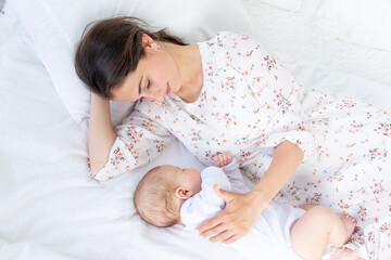 mom and newborn baby sleep together, mom puts baby to sleep on the bed in the bedroom, the concept...