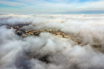 Top aerial view of fluffy white clouds over modern city with high rise buildings