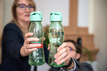 Close-up of two business people hands holding plastic mineral water bottles,healthy lifestyle,water drinking concept