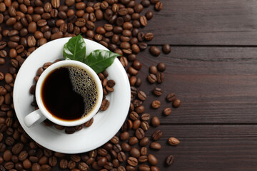 Cup of aromatic coffee and beans on wooden table, flat lay. Space for text