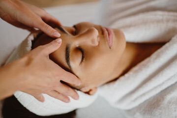 Closeup of beautiful African American woman in spa salon getting face treatment.