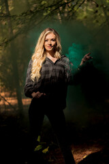 Obraz na płótnie Canvas A Lovely Blonde Model Holds A Lantern With Smoke Flowing Out Of It In A Moody Forrest Environment