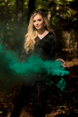Fototapeta na wymiar A Lovely Blonde Model Holds A Lantern With Smoke Flowing Out Of It In A Moody Forrest Environment