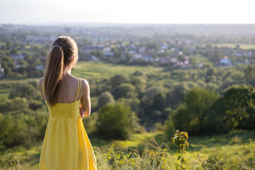 Young woman in summer dress standing outdoors enjoying warm day.