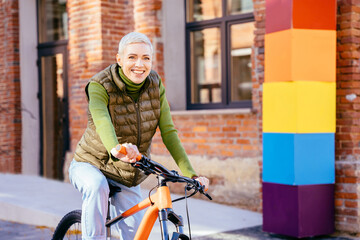 Cheerful adult 40-45 year old woman enjoy bike ride in sunny urban outdoor leisure activity in the...