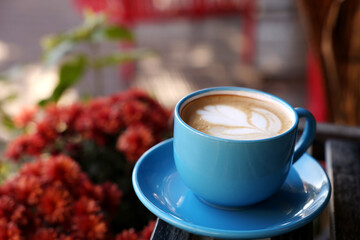 Ceramic cup of aromatic coffee with foam on wooden table in outdoor cafe. Space for text