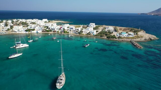 Aerial drone rotational video of picturesque fishing village of Polonia with traditional fishing boats anchored next to island of Kimolos, Milos island, Cyclades, Greece