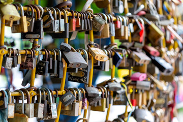 Many different metal locks hung by couples in love on the wall of lovers.