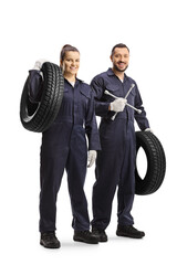 Male and female auto mechanic workers holding lug wrench tool and a car tire