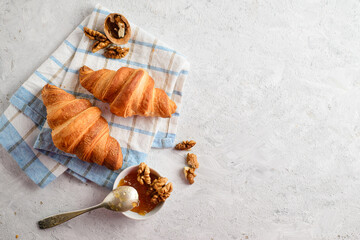 Two fresh croissants, jam and walnuts on a blue plaid towel top view, close-up, copy space