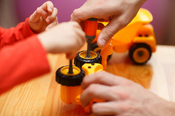 father and son's hands putting toy cars together