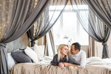 Obraz na płótnie Canvas Cheerful couple awaking and looking at each other in bed