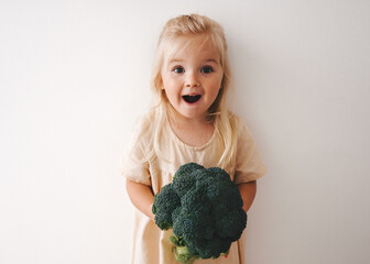 Surprised girl with broccoli healthy food vegan child family lifestyle organic vegetables harvest...