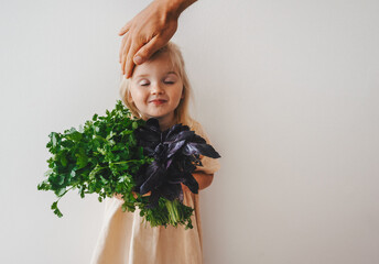 Little girl child with coriander and basil bunch healthy vegan food organic farm gardening plant...