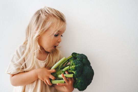 Child girl with broccoli healthy food vegan eating lifestyle organic vegetables vitamins plant based diet raw nutrition funny kid surprised emotions