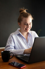 Young woman is smiling and chatting online on a laptop at home or in the office. Concept of studying or working from home online.