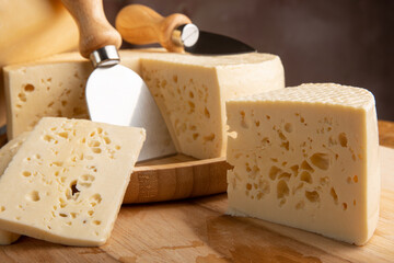 Semi-cured cheese from Brazil, beautiful Brazilian cheeses and cutting accessories arranged on light rustic wood, selective focus.