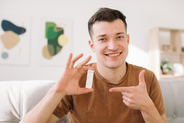 Young man checks for covid-19 test while sitting on sofa at home.