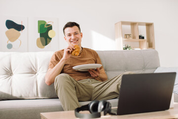 Portrait of a handsome happy blogger using his laptop during breakfast.