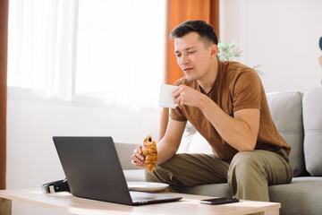 Portrait of a handsome happy blogger using his laptop during breakfast.