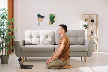 Man doing exercise while watching tutorial on laptop at home