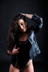 Young beautiful woman in black bodysuit posing in studio on black background