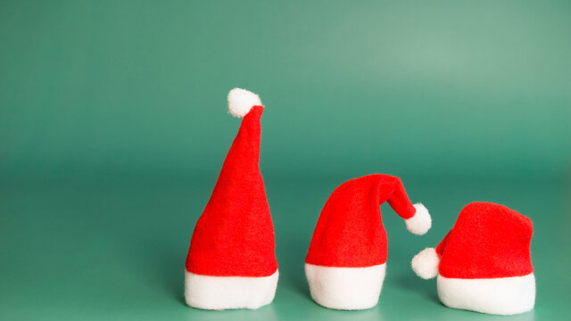 Three bright santa claus cap on a green background