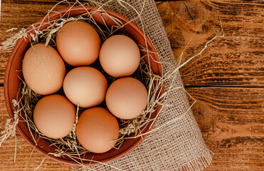 Fresh organic eggs in bowl on wooden rustic background. Directly above, copy space.