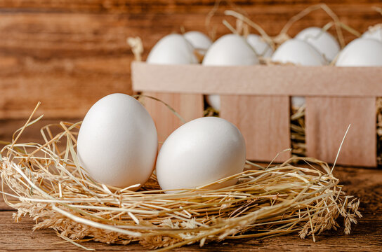 Fresh chicken eggs on hay on wooden background. Organic food concept