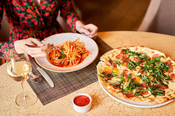 Woman eats Italian pasta with tomato, meat. Close-up spaghetti Bolognese wind it around a fork with...