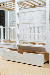 Obraz na płótnie Canvas The image of the child's bed, bottom view of the storage drawers. White beautiful furniture, Vertical photo.