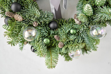 Beautiful festive wreath of fresh spruce on Gray wall. Xmas circlet with ornaments and balls. Christmas mood.
