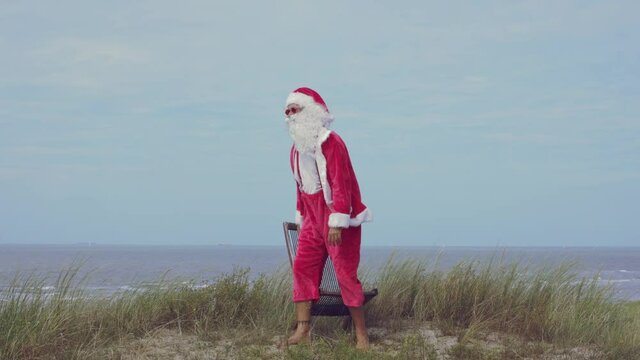 santa claus looks at the horizon with open arms enjoying the view - seashore in background