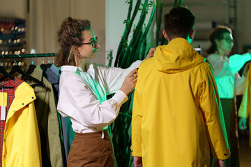 Outerwear clothes designer making measures for sewing raincoat in atelier. Female tailor measuring client for bespoke trendy jacket. Young needlewoman work on new clothing collection in workshop room